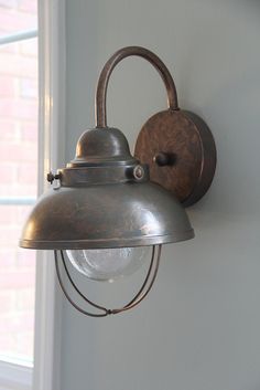 an old fashioned wall light hanging on the side of a house in front of a window