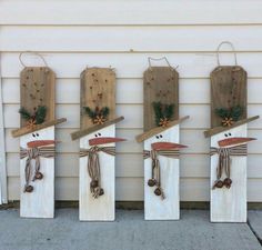 four snowmen made out of wooden boards and tied with twine, pine cones and bows