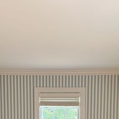 a bedroom with striped wallpaper and a window in the corner that has a cat sleeping on it