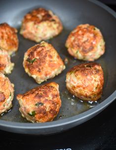 some crab cakes are cooking in a pan on the stove top with water running through them