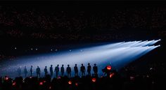 a group of people standing on top of a stage under a spotlight filled with bright lights