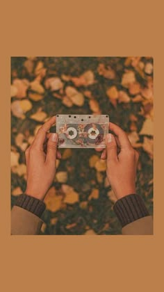 someone holding up a cassette in front of leaves