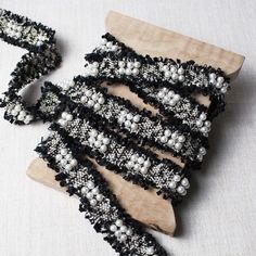 several pieces of black and white beaded fabric sitting on top of a wooden board