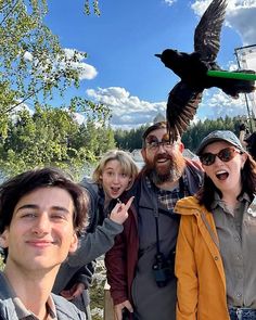 a group of people standing next to each other in front of a bird feeder on a tree