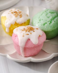 three different colored pastries on a plate with spoons and plates in the background