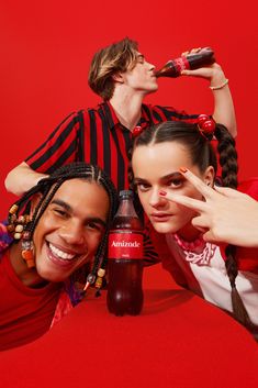 three young people posing for the camera with coca cola bottles in front of their faces