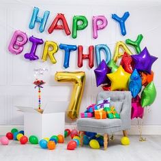 a birthday party with balloons and presents on the floor next to a number seven balloon wall