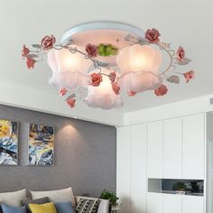 a living room filled with lots of furniture and flowers hanging from the ceiling above it