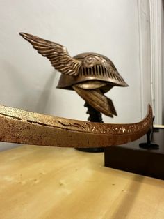 a bronze bird sculpture sitting on top of a wooden table