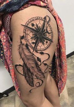 a woman's thigh with a tattoo on it that has a compass and a feather