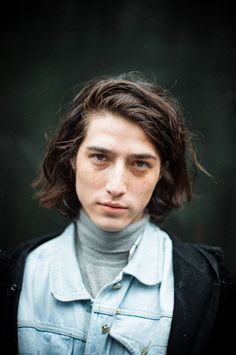 a young man with long hair wearing a blue shirt