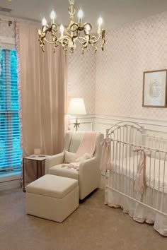 a baby's room with a white crib, chair and chandelier