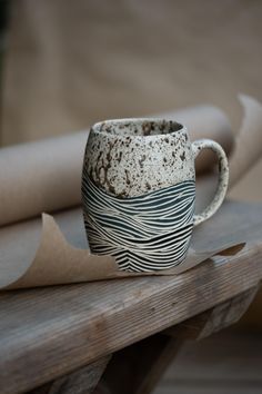 a coffee cup sitting on top of a wooden table next to some brown paper rolls