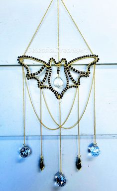 a gold and black beaded necklace hanging from a wall