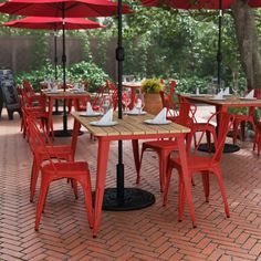 an outdoor dining area with red chairs and tables covered by umbrellas on brick patio