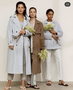 three women standing next to each other holding flowers