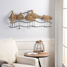 three birds are hanging on the wall next to a table with a birdcage