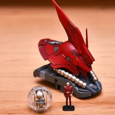 a small toy figure next to a red model ship