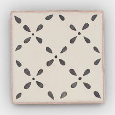 a white and black square tile with some black leaves on it's surface,