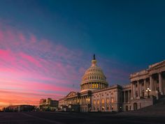 the capitol building in washington, dc at dusk with pink and blue skies above it