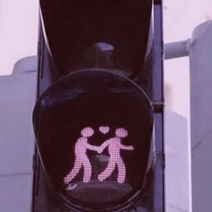 a traffic light with a pink crosswalk sign on it's face and two people holding hands