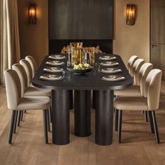 a dining room table is set with plates and silverware, along with beige upholstered chairs