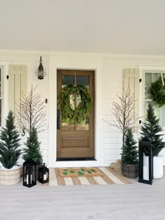 front porch decorated for christmas with evergreen wreaths and potted trees on either side