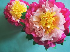 two pink and yellow paper flowers on a blue background