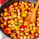 a pan filled with cubed food and a wooden spoon on top of the pot