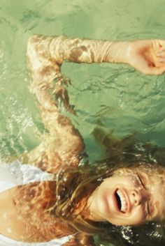 a woman is floating in the water with her arms outstretched