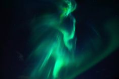 an aurora bore is seen in the night sky with green and blue lights above it