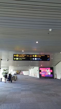 people are walking through an airport terminal with their luggage and baggage claim signs above them