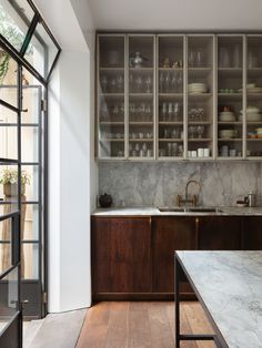 a kitchen with marble counter tops and wooden cabinetry, along with shelves filled with dishes