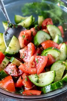 a glass bowl filled with cucumber and tomato salad