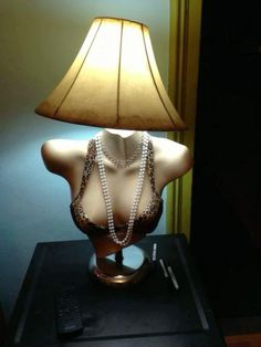 a mannequin with pearls and a lamp on a table in a hotel room