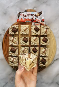 a person holding up a piece of food in front of a plate with chocolate and marshmallows on it