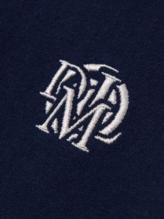 the monogrammed logo is shown in white on a navy polo shirt