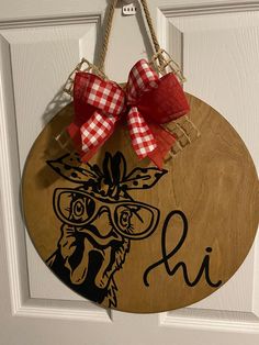 a wooden sign with a red bow hanging from it's side on a door