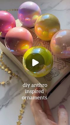 a person touching some soap balls on top of a book with the words diy anthro inspired ornaments