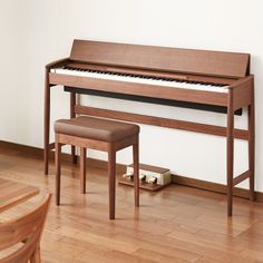 a wooden piano sitting on top of a hard wood floor next to a chair and ottoman