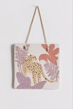 a white and pink wall hanging with a cheetah on it's side