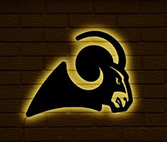 the rams logo is lit up on a brick wall in front of a yellow light