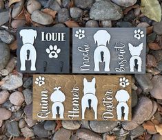 two wooden signs with dogs on them sitting next to some rocks and leaves in the background