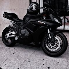 a black and white photo of a motorcycle parked in front of a building on the sidewalk