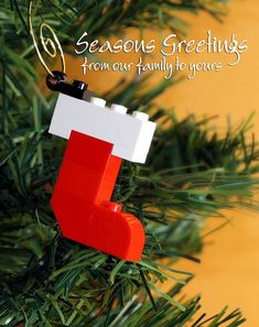 a lego christmas ornament hanging from a tree with the words seasonal greetings from our family to yours