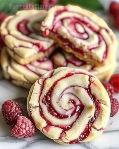 raspberry swirl cookies on a marble surface with fresh raspberries around them