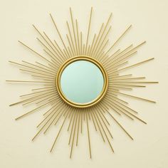 a gold sunburst mirror mounted to the side of a wall