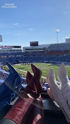 two women's shoes sitting on the edge of a bench at a football game