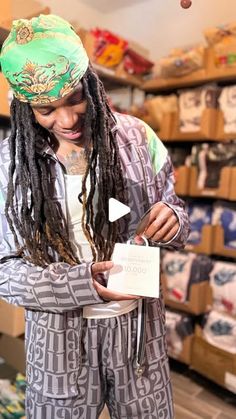 a man with dreadlocks standing in a store looking at a piece of paper