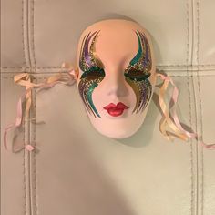 a mask is hanging on the wall with ribbons around it's face and eyes